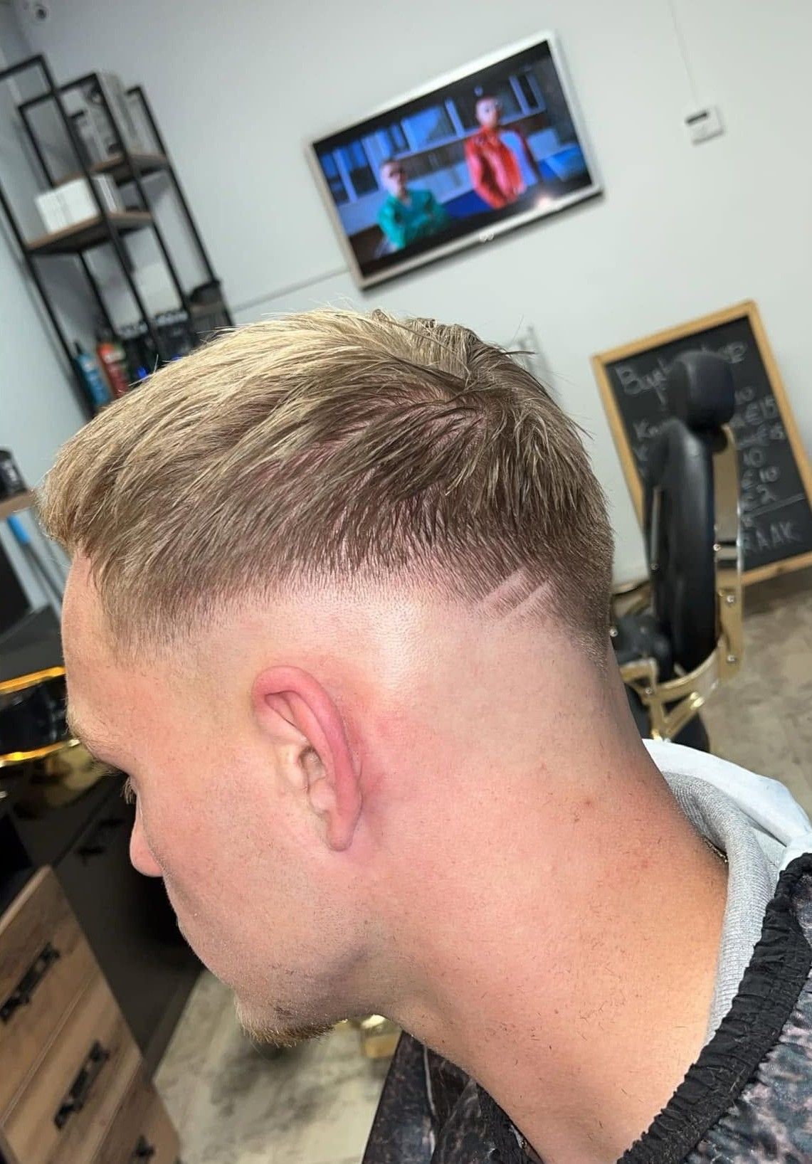 Blond kort kapsel met textuur bovenop, een hoge fade en een lijn aan de zijkant