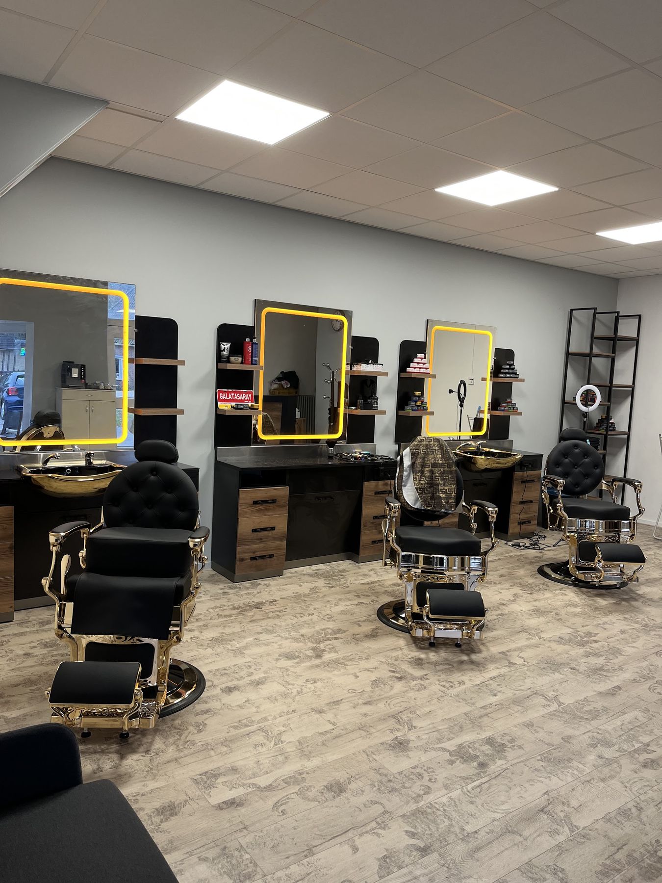 De drie barberstoelen van Barbershop Duran met gouden wastafels en verlichte spiegels
