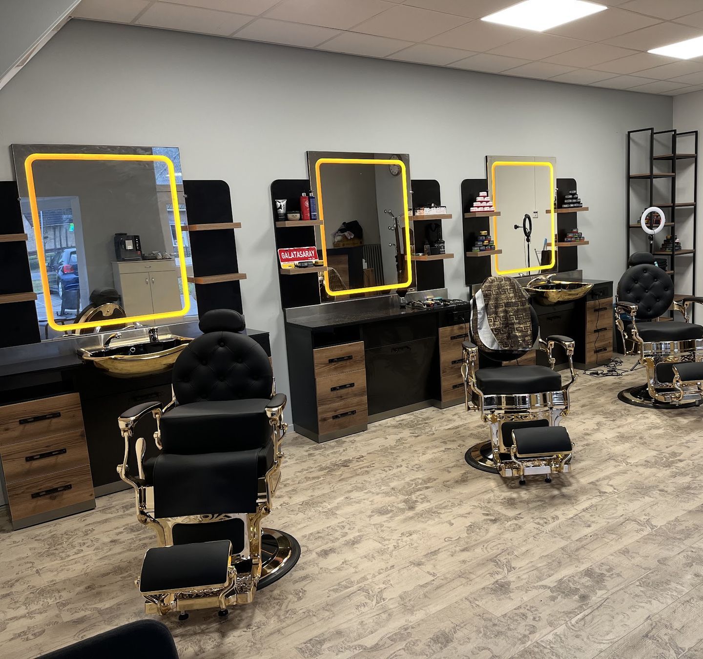 De barbershop van Duran met drie zwart-gouden barberstoelen en verlichte spiegels